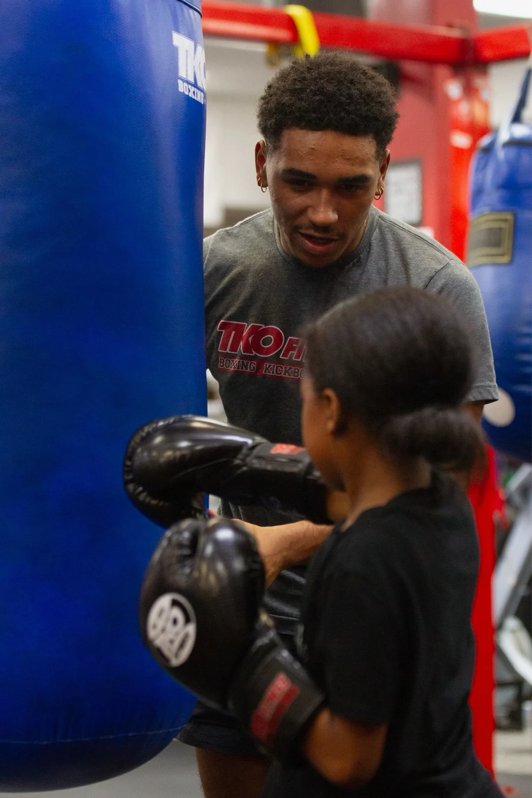 Coach helping a young boxer train on a heavy bag